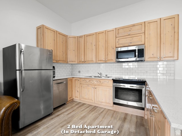 kitchen featuring light countertops, a sink, light brown cabinetry, appliances with stainless steel finishes, and light wood-style flooring