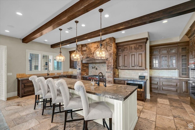 2255 S Hill Rd Unit 14, St George, UT 84790 - kitchen featuring stone tile floors, a center island with sink, visible vents, a breakfast bar, and tasteful backsplash