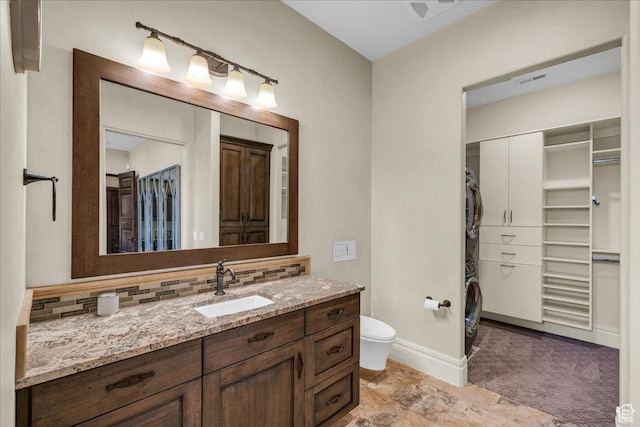 2255 S Hill Rd Unit 14, St George, UT 84790 - full bath with vanity, baseboards, stacked washing maching and dryer, toilet, and backsplash