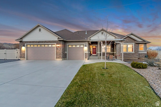 view of front of house featuring fence, a front lawn, driveway, stone siding, and a garage