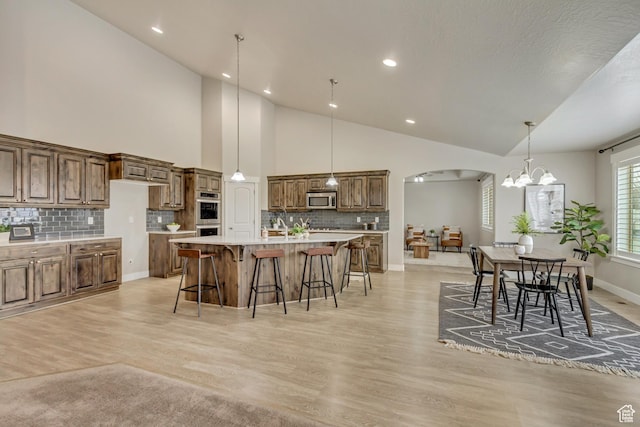 1879 E Tickville Cir, Eagle Mountain, UT 84005 - kitchen featuring stainless steel appliances, an inviting chandelier, backsplash, arched walkways, and a kitchen bar