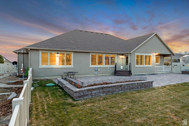 1879 E Tickville Cir, Eagle Mountain, UT 84005 - back of house at dusk featuring a gate, fence, a yard, a patio, and stucco siding