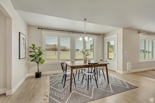 1879 E Tickville Cir, Eagle Mountain, UT 84005 - dining area featuring arched walkways, baseboards, visible vents, a notable chandelier, and light wood-style floors