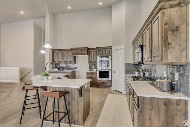 1879 E Tickville Cir, Eagle Mountain, UT 84005 - kitchen featuring a high ceiling, light wood finished floors, stainless steel appliances, a sink, and tasteful backsplash