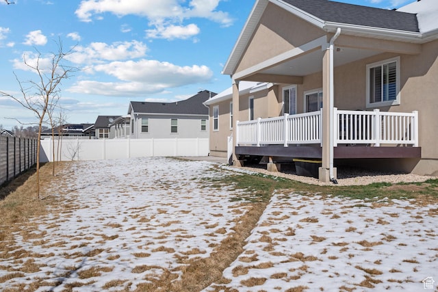view of snow covered exterior featuring a fenced backyard and stucco siding