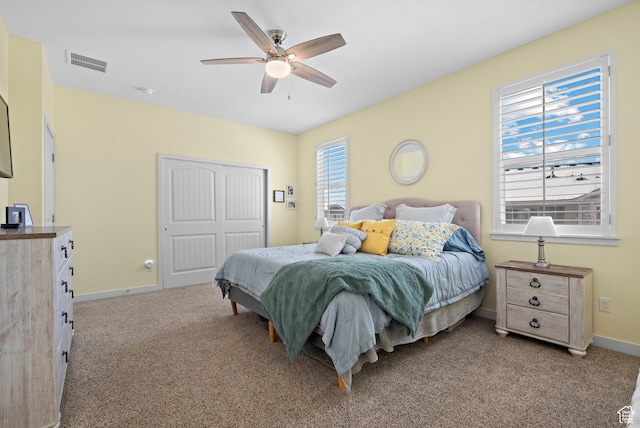 carpeted bedroom with baseboards, ceiling fan, a closet, and visible vents