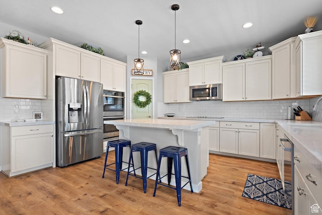kitchen with backsplash, stainless steel appliances, white cabinetry, and a kitchen breakfast bar
