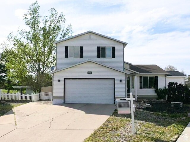 view of front of property with an attached garage, fence, and concrete driveway