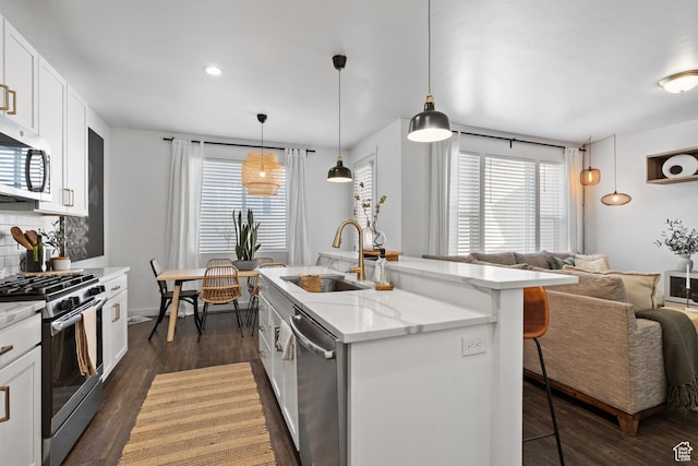 kitchen with a sink, tasteful backsplash, a kitchen breakfast bar, stainless steel appliances, and dark wood-style flooring