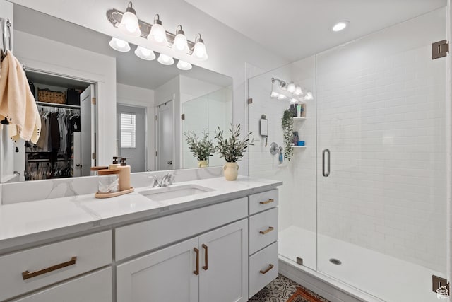 bathroom featuring a stall shower, a spacious closet, and vanity
