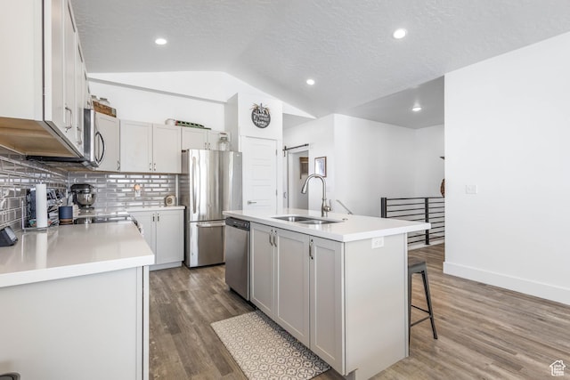 671 W 660 S, Tooele, UT 84074 - kitchen with decorative backsplash, appliances with stainless steel finishes, a sink, lofted ceiling, and a center island with sink