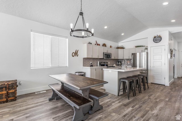 671 W 660 S, Tooele, UT 84074 - kitchen featuring a textured ceiling, appliances with stainless steel finishes, a chandelier, vaulted ceiling, and wood finished floors