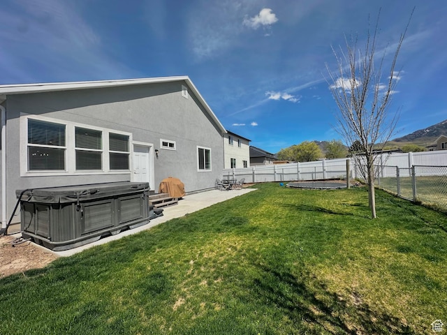 671 W 660 S, Tooele, UT 84074 - back of property featuring a fenced backyard, stucco siding, a hot tub, a patio, and a lawn