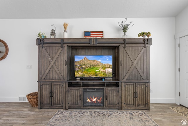 671 W 660 S, Tooele, UT 84074 - room details with wood finished floors, visible vents, a warm lit fireplace, and baseboards