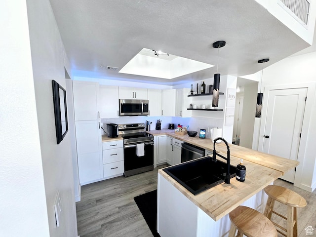 900 Bitner Rd Unit G-32, Park City, UT 84098 - kitchen with visible vents, a tray ceiling, light wood-style flooring, appliances with stainless steel finishes, and open shelves