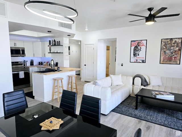living area with visible vents, a ceiling fan, and light wood-style floors