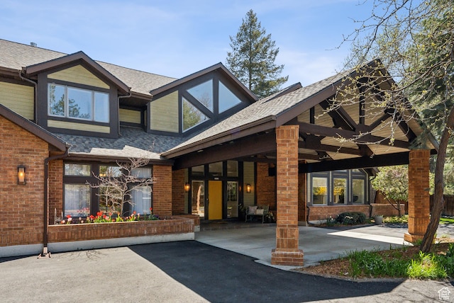 exterior space featuring brick siding and a shingled roof