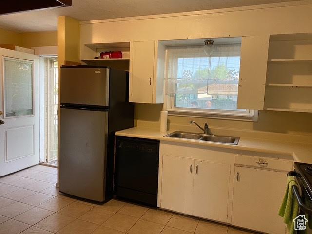 kitchen featuring a sink, open shelves, black dishwasher, freestanding refrigerator, and light countertops