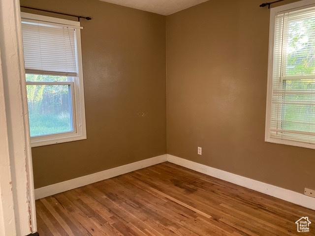 spare room with baseboards and wood finished floors