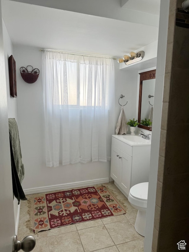 bathroom featuring tile patterned flooring, vanity, baseboards, and toilet
