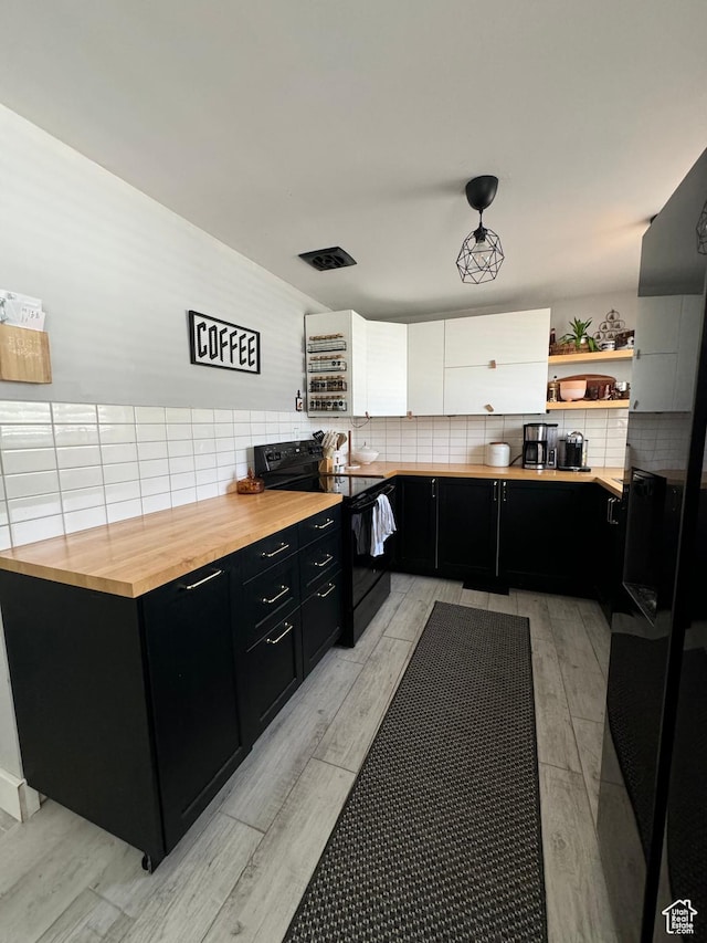 kitchen with light wood-style floors, dark cabinets, butcher block countertops, backsplash, and electric range
