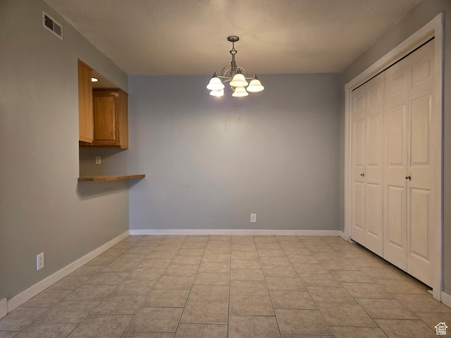 unfurnished dining area with a chandelier, light tile patterned flooring, and baseboards