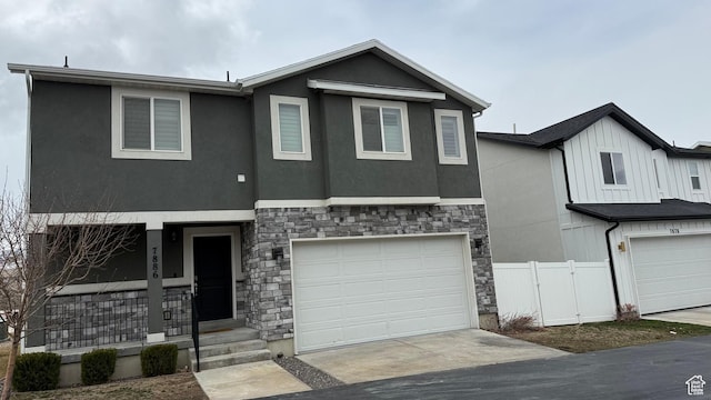 view of front of house featuring a garage, stone siding, stucco siding, and fence