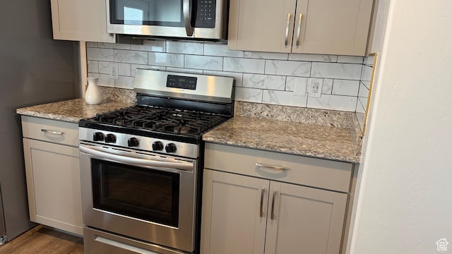 7886 S Fauna Ln W, West Jordan, UT 84081 - kitchen featuring light stone counters, backsplash, appliances with stainless steel finishes, and wood finished floors