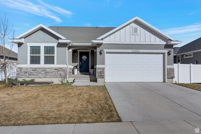 view of front facade with fence, driveway, stucco siding, a garage, and stone siding