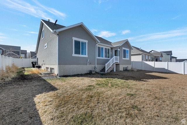 back of property featuring a yard, a residential view, stucco siding, and a fenced backyard