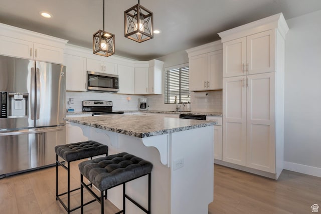 kitchen featuring backsplash, a kitchen island, a breakfast bar area, white cabinets, and stainless steel appliances