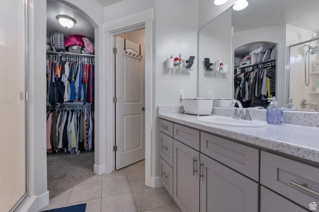 bathroom featuring vanity, a shower stall, a walk in closet, and tile patterned flooring