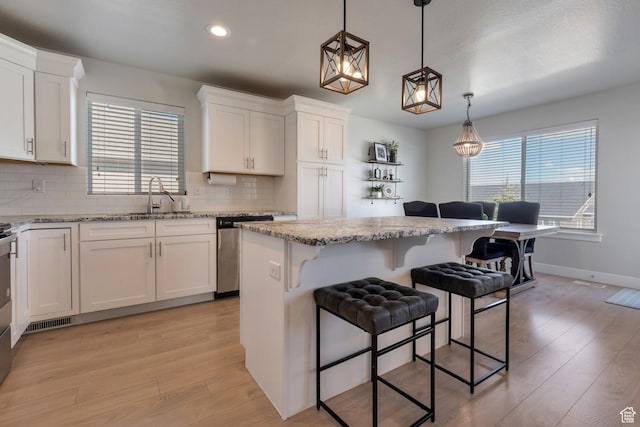 kitchen featuring a sink, white cabinets, light wood-style floors, and stainless steel dishwasher
