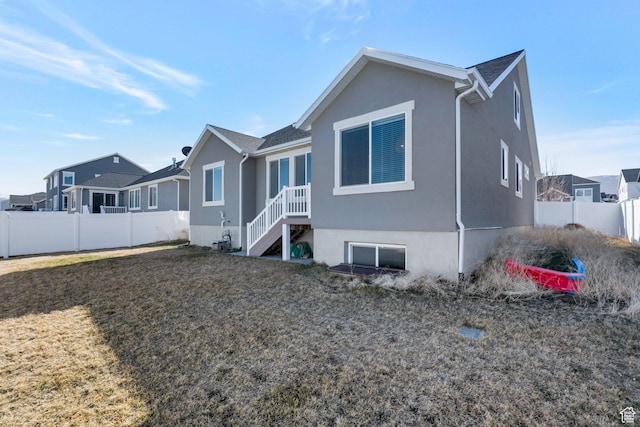 back of property with fence, a lawn, and stucco siding