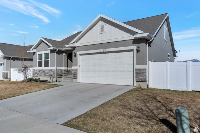 view of front of home featuring fence, an attached garage, concrete driveway, stone siding, and board and batten siding