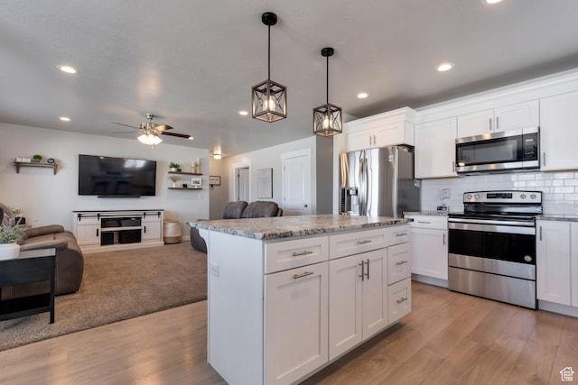 kitchen featuring light wood-style flooring, a kitchen island, tasteful backsplash, open floor plan, and appliances with stainless steel finishes
