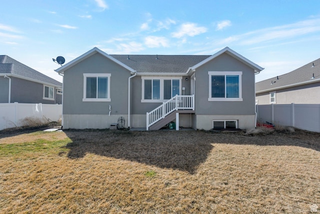 rear view of house with a yard and fence