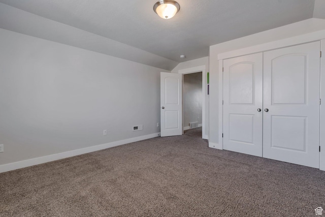 unfurnished bedroom with carpet, visible vents, baseboards, vaulted ceiling, and a closet