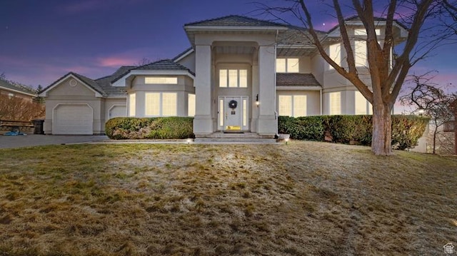 view of front facade with stucco siding, concrete driveway, an attached garage, and a tiled roof