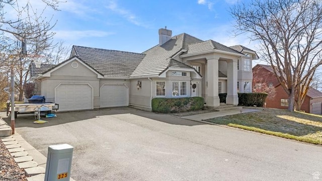 315 Stonehenge, Providence, UT 84332 - view of front of home with driveway, stucco siding, a chimney, a garage, and a tile roof