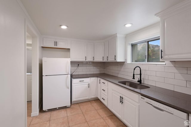kitchen featuring white appliances, light tile patterned floors, dark countertops, and a sink