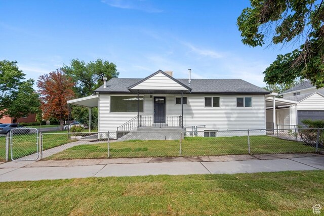 bungalow-style house featuring an attached carport, a front lawn, a gate, and a fenced front yard
