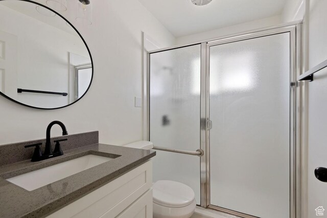 bathroom featuring a shower stall, toilet, and vanity