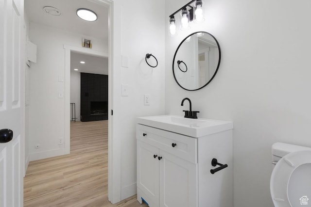 210 Ogden Cyn, Ogden, UT 84401 - half bathroom featuring toilet, wood finished floors, baseboards, a brick fireplace, and vanity