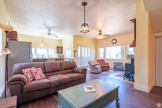 living room featuring dark wood-style floors, baseboards, a textured ceiling, and ceiling fan