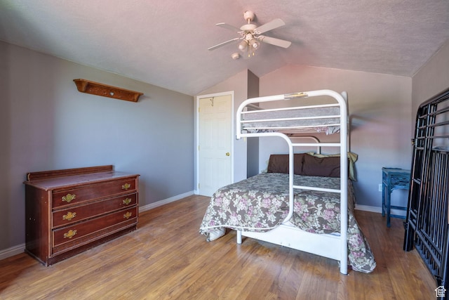 bedroom with baseboards, lofted ceiling, wood finished floors, and a ceiling fan