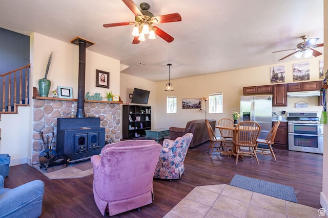 living area featuring wood finished floors, ceiling fan, and a wood stove