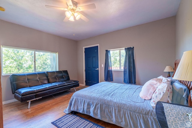 bedroom with a ceiling fan, wood finished floors, and baseboards