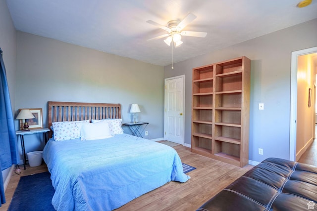 bedroom featuring baseboards, wood finished floors, and a ceiling fan