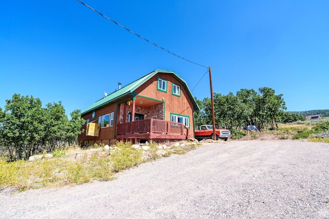 view of front of house featuring a gambrel roof and a wooden deck
